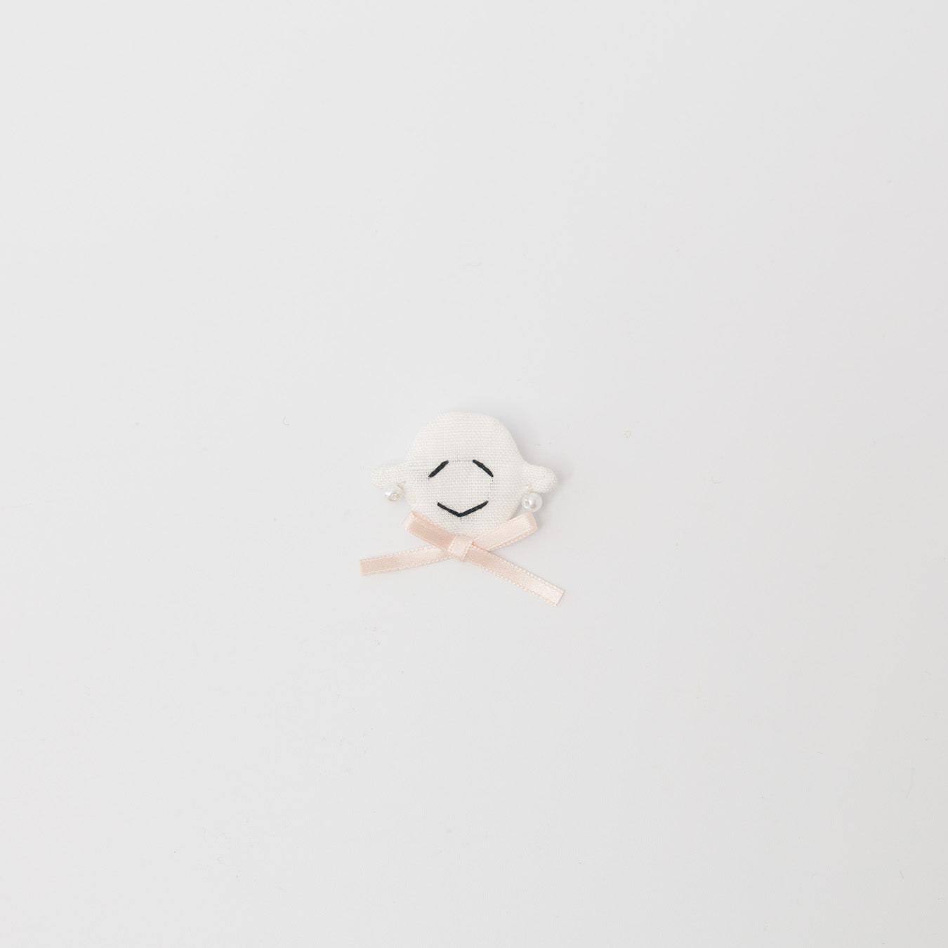 "あんこちゃん"の顔ブローチ付き。パールのイヤリングとリボンを身に着けた装い。