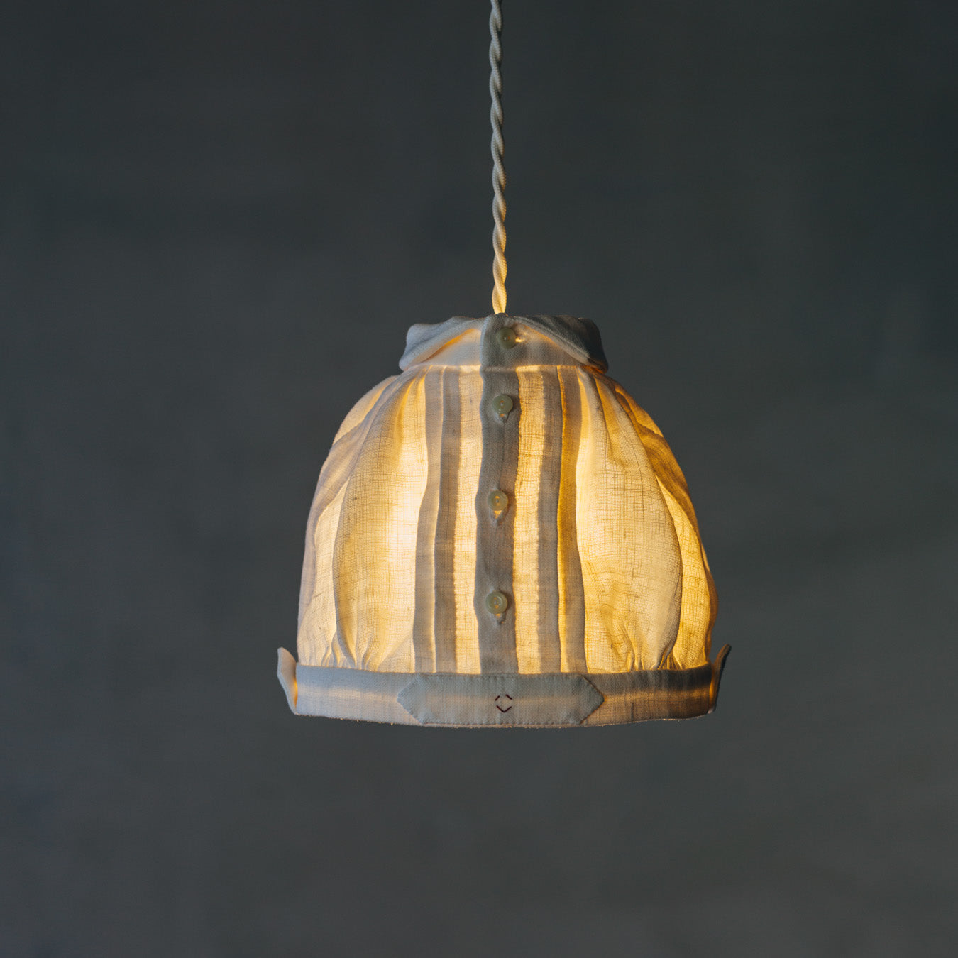 アンティークリネンで仕立てた、お洋服のようなランプシェードです。やわらかな灯りが、リネンのタックやギャザーの陰影を引き立てます。