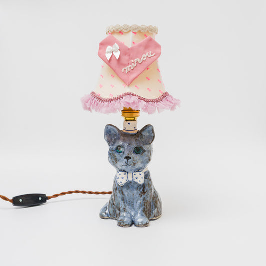 穏やかな表情が魅力的なグレー猫の台座に、“minou”の刺繍を施したハートモチーフのシェードを合わせた、ロマンチックで愛らしい雰囲気のテーブルランプです。